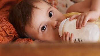 Baby drinking formula looking at camera.