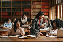Japanese female professor standing next to student and explaining a concept.
