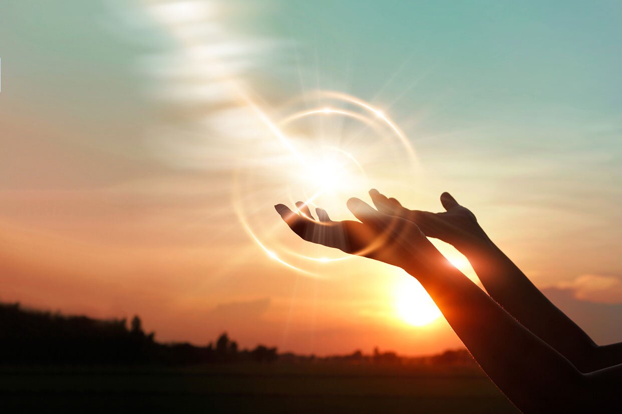 Hands raised to sunset in prayer.